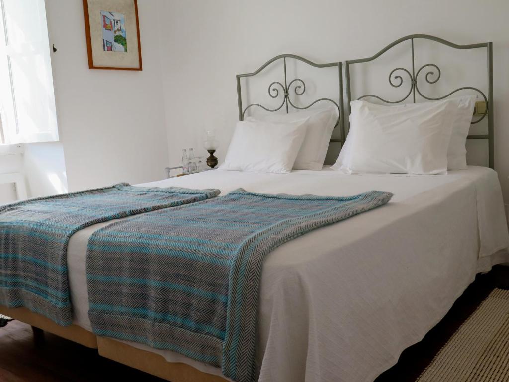 a bedroom with a large white bed with a blue blanket at Quinta das Buganvílias in Castelo Branco