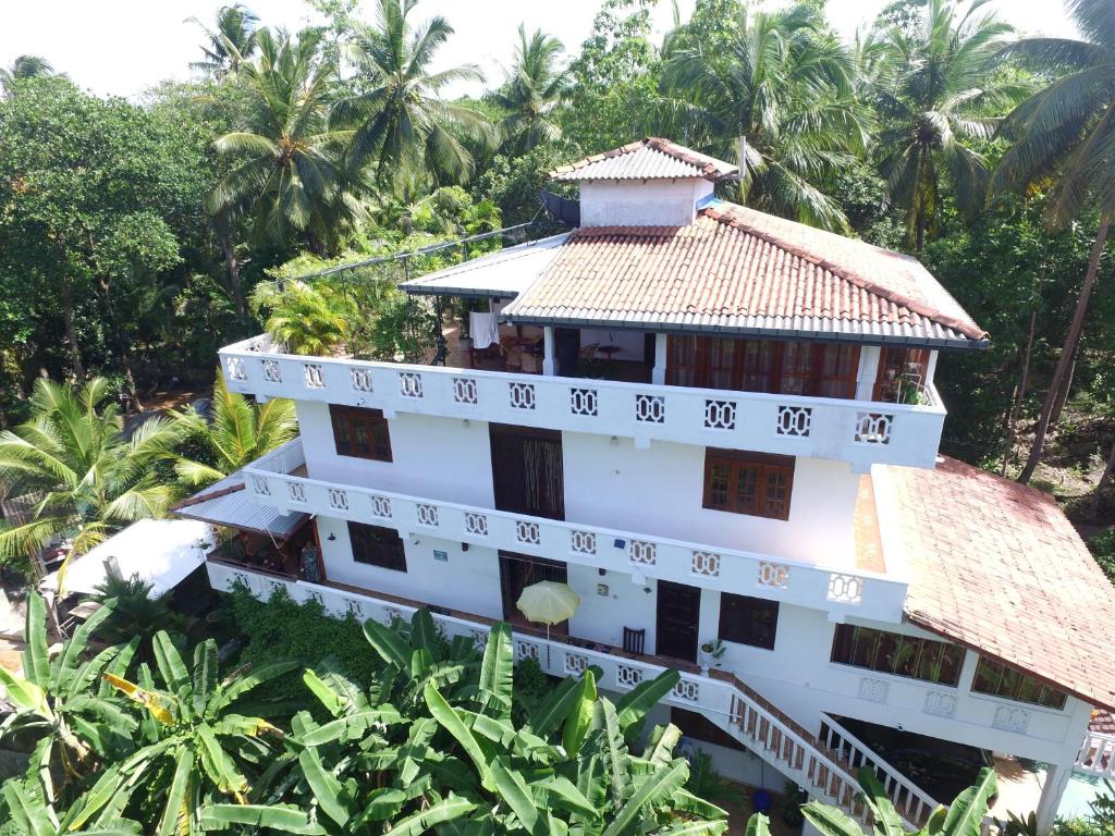 a white building with a tile roof and palm trees at White Villa in Unawatuna