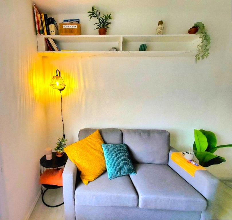 - un salon avec un canapé gris et des oreillers colorés dans l'établissement Appartement cosy proche mer, à Les Sables-dʼOlonne