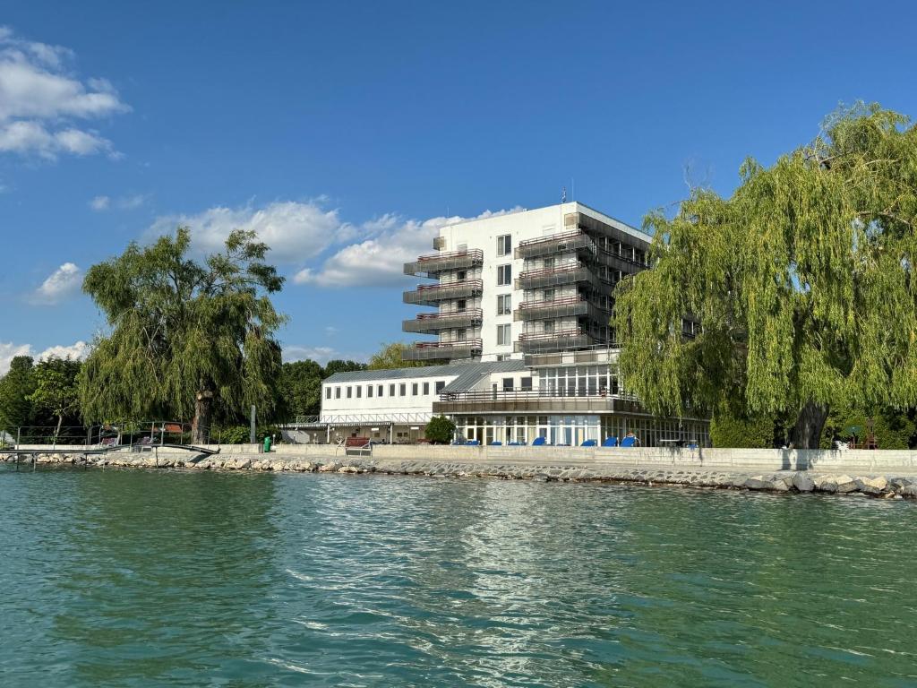 a building on the shore of a body of water at Világos Hotel Balatonvilágos in Balatonvilágos