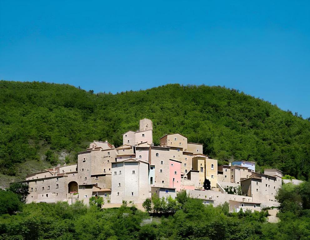 un grand bâtiment au sommet d'une colline dans l'établissement Castello Di Postignano Relais, à Sellano