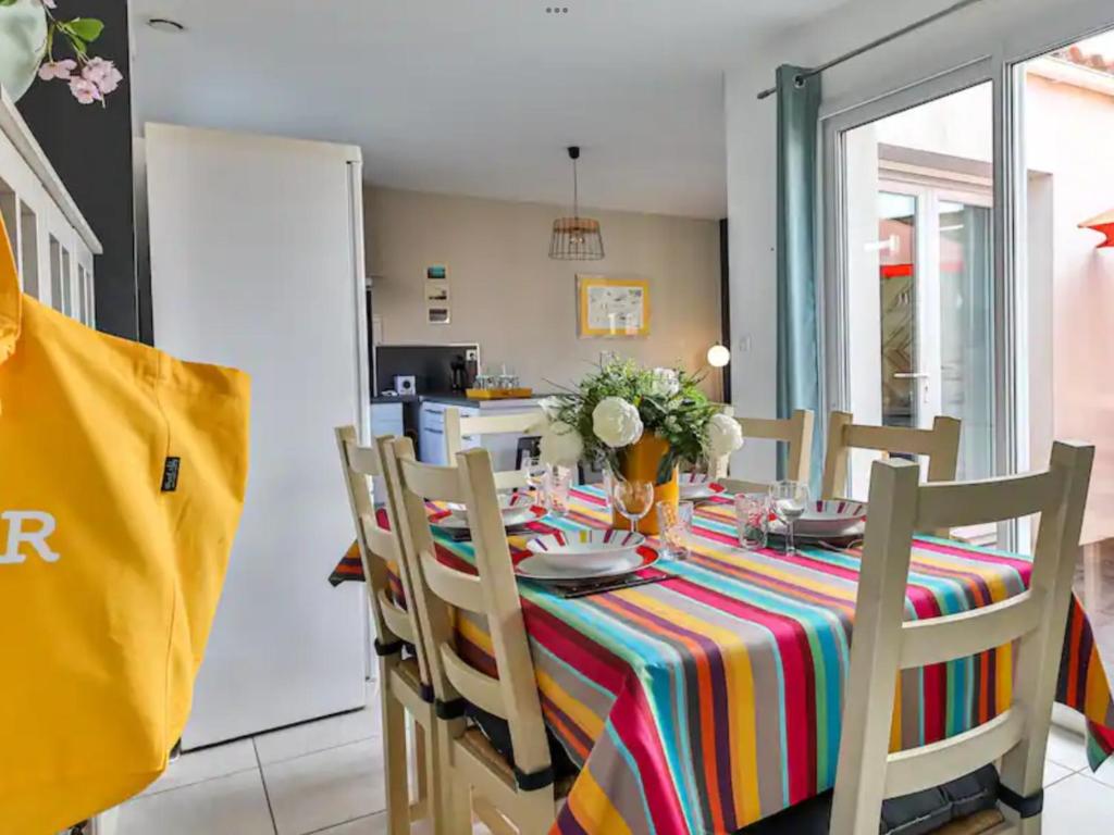 une salle à manger avec une table et des chaises colorées dans l'établissement Maison Les Agapanthes, à Les Sables-dʼOlonne