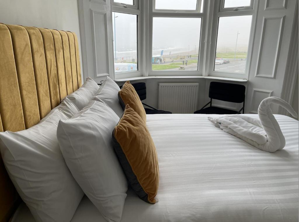 a bedroom with a bed with white pillows and windows at The Norton- Hartlepool in Seaton Carew