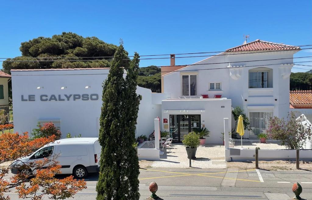 a white building with a van parked in front of it at Hôtel le Calypso in Hyères