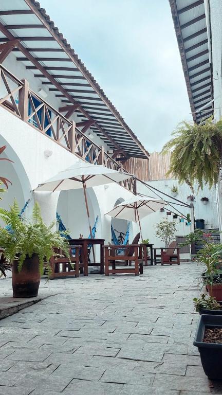 a patio with tables and umbrellas in a building at Vila Mucugê Pousada e Hostel in Arraial d'Ajuda
