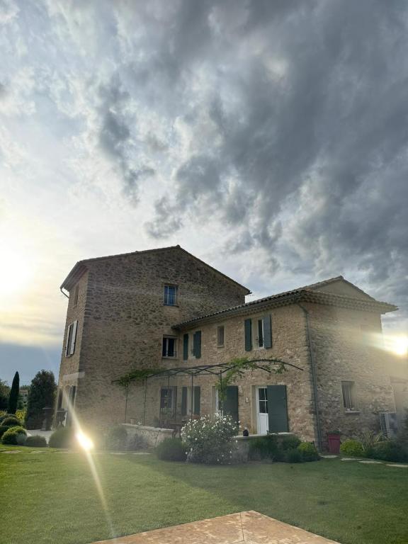 un grand bâtiment en pierre dans un champ avec un ciel nuageux dans l'établissement Les Oliviers De Notre Dame, à Mazan