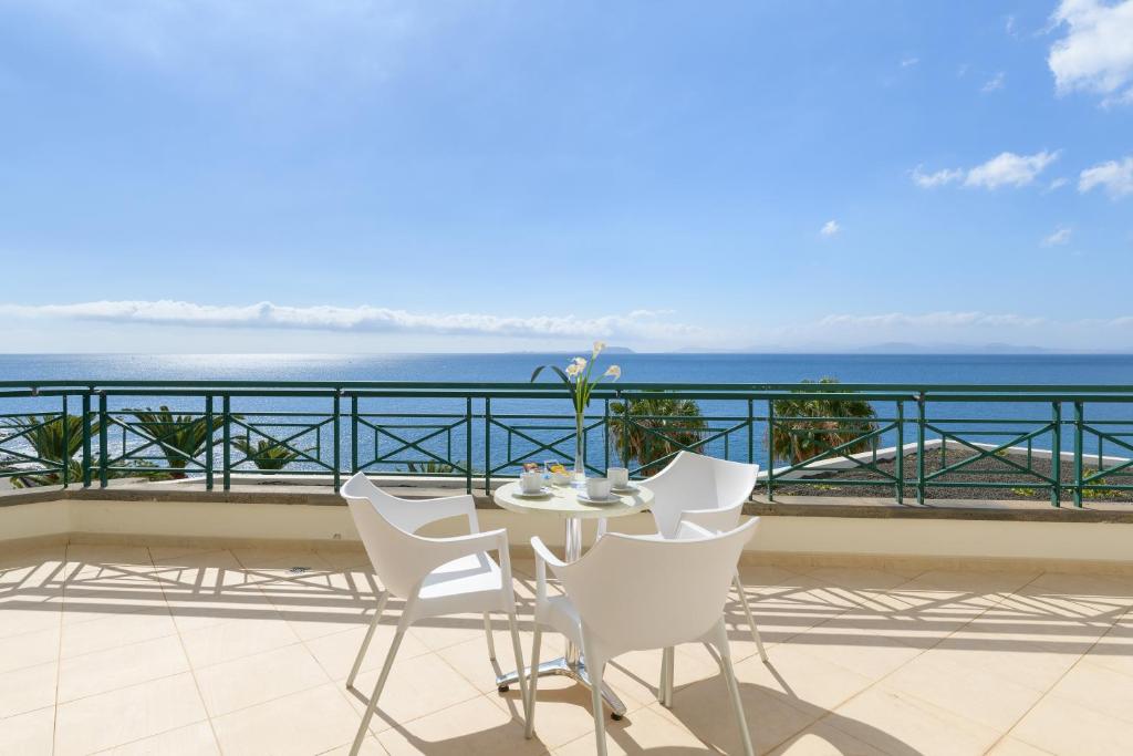 a table and chairs on a balcony overlooking the ocean at Hipotels Natura Palace Adults Only in Playa Blanca