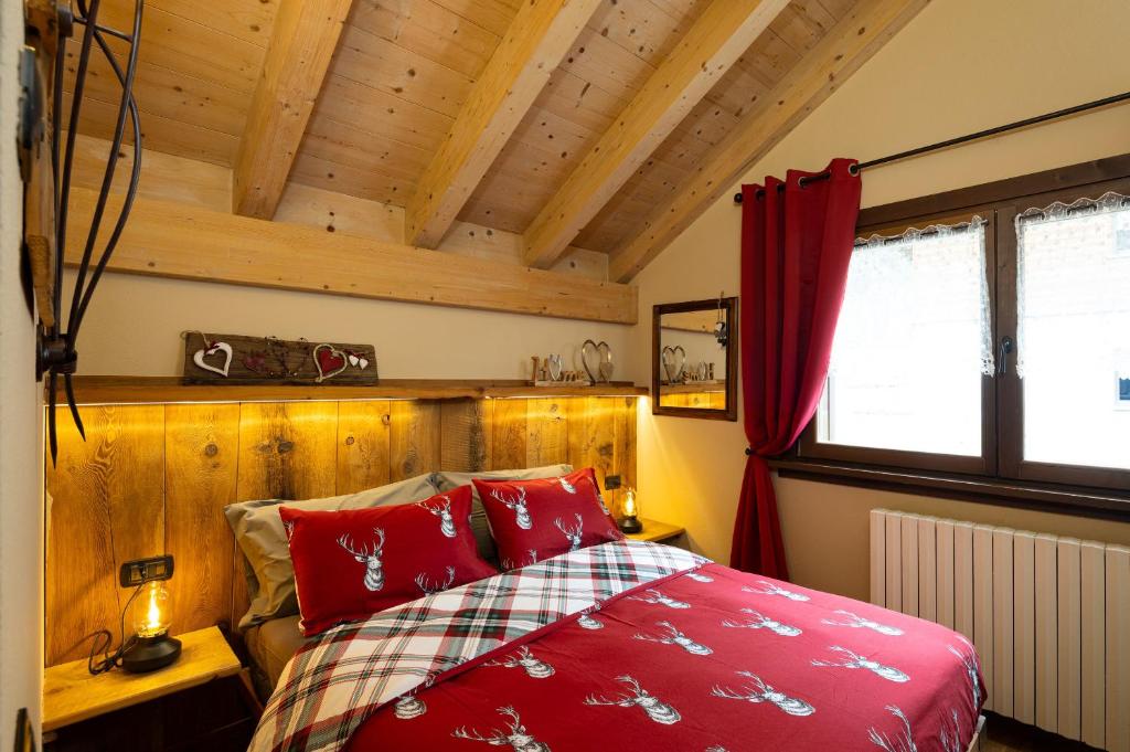a bedroom with a red bed and wooden walls at Chalet Da Florin in Livigno