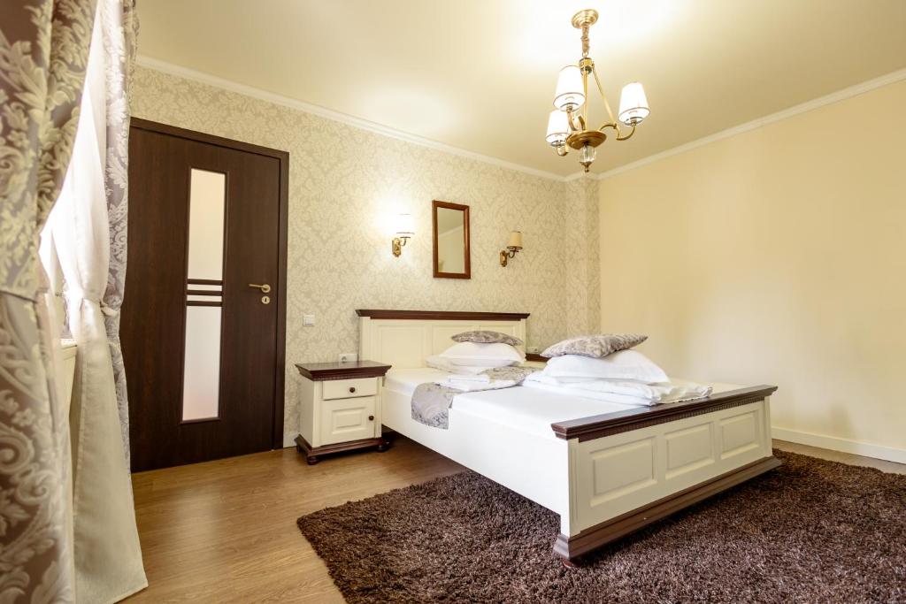 a bedroom with a large white bed and a chandelier at Green Garden Avrig in Avrig