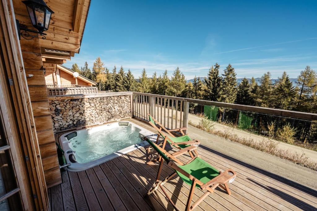 a deck with a hot tub and two chairs at Almhütten Skorianz- Die Grüne Hirschhütte in Klippitztorl