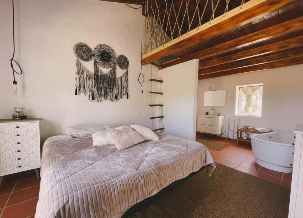 a bedroom with a large bed and a bath tub at Herdade da Maceira in São Luis