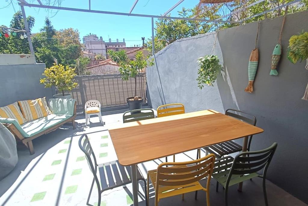 une table et des chaises en bois sur une terrasse dans l'établissement Duplex atypique avec terrasse, à Marseille