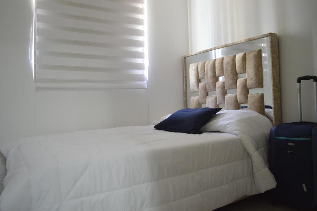 1 dormitorio con cama con almohada azul y ventana en Apartamento Treboles en Cali
