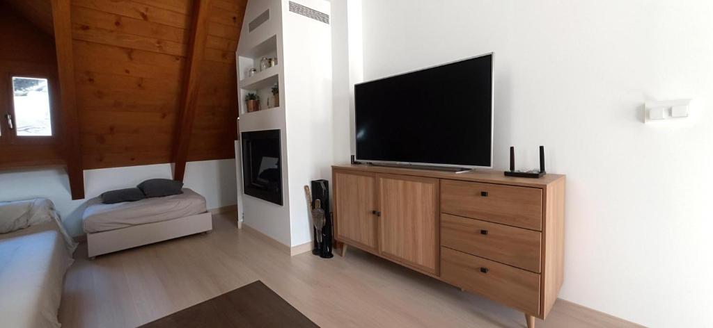 una sala de estar con TV de pantalla plana en una cómoda de madera en Apartamento centro de Sallent con WIFI, en Sallent de Gállego