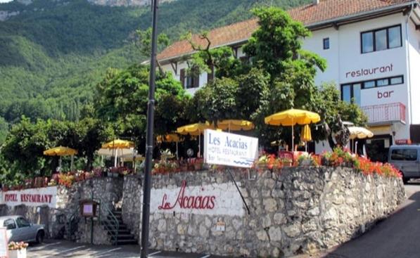 un restaurant avec des parasols sur un mur en pierre dans l'établissement Hotel Restaurant - Acacias Bellevue, à Veyrier-du-Lac