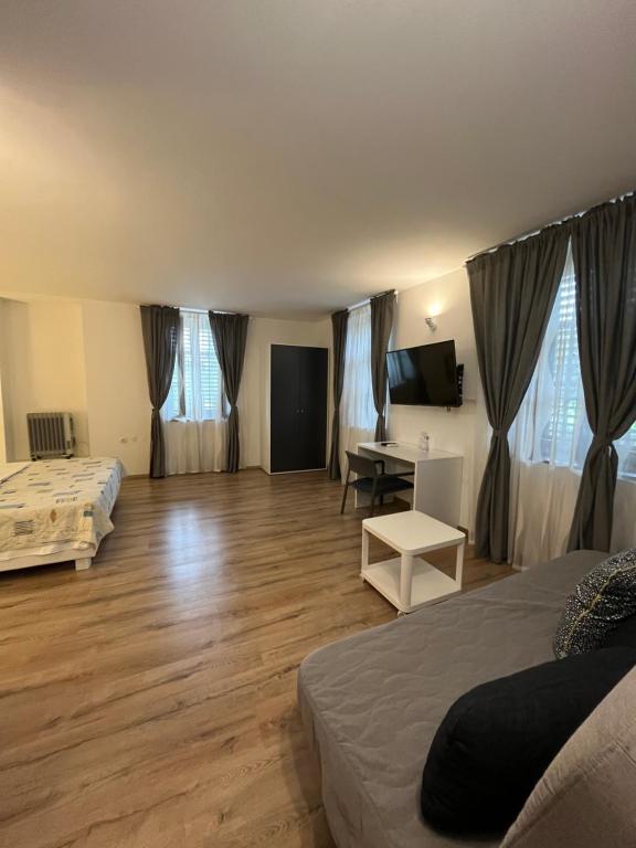 a room with two beds and a desk and a television at Hotel Paquito in Nova Gorica