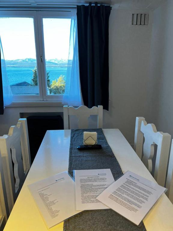 a table with a book on it in front of a window at Los Dones Departamentos DAT in San Carlos de Bariloche