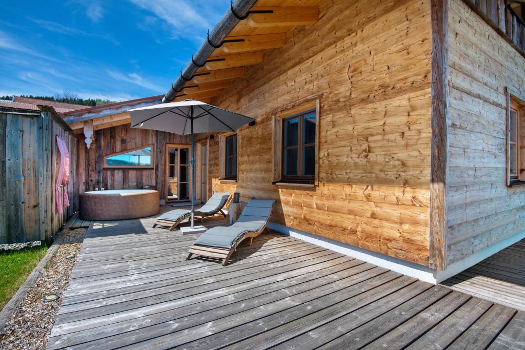 a wooden deck with two chairs and an umbrella at Bergchalet 2 in Freyung