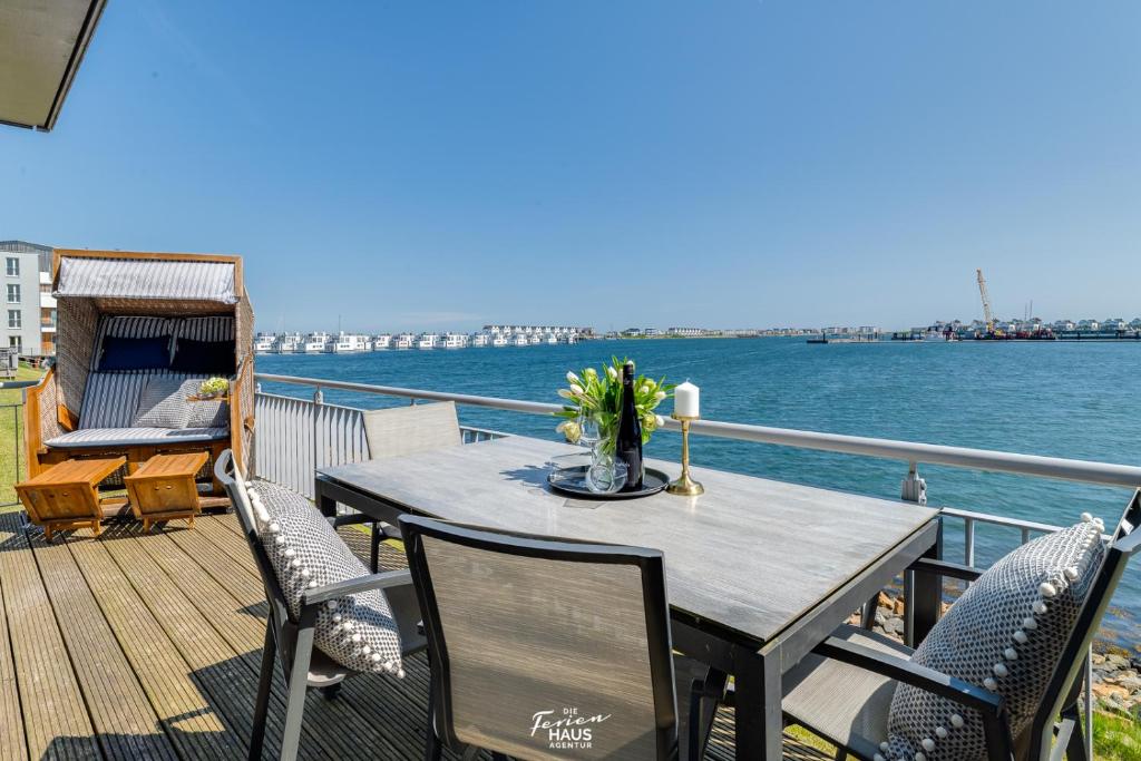 a table and chairs on a deck with the water at Palstek in Olpenitz