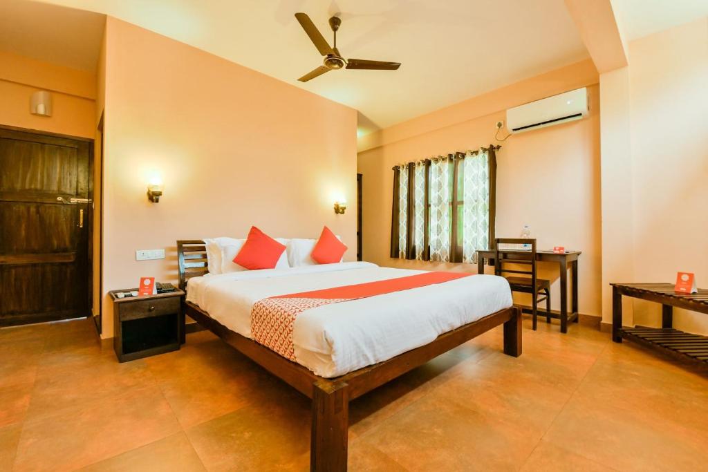 a bedroom with a large bed and a desk at OYO 13415 Cherai Village Home Stay in Cherai Beach