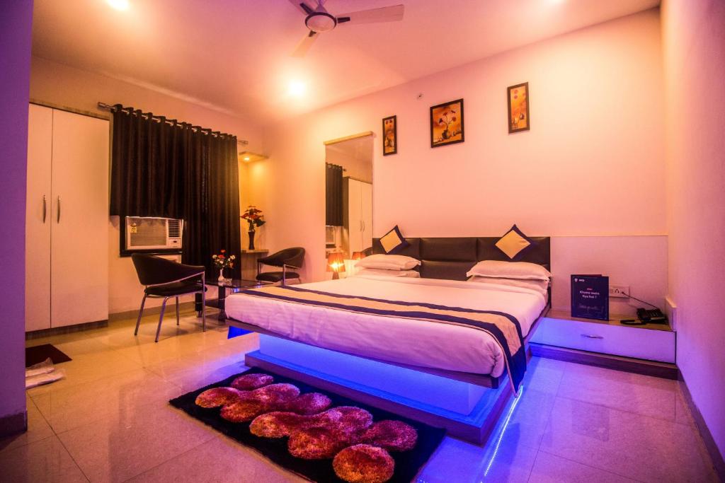um quarto com uma cama grande e iluminação roxa em Capital O 5764 A Park Hotel em Gwalior