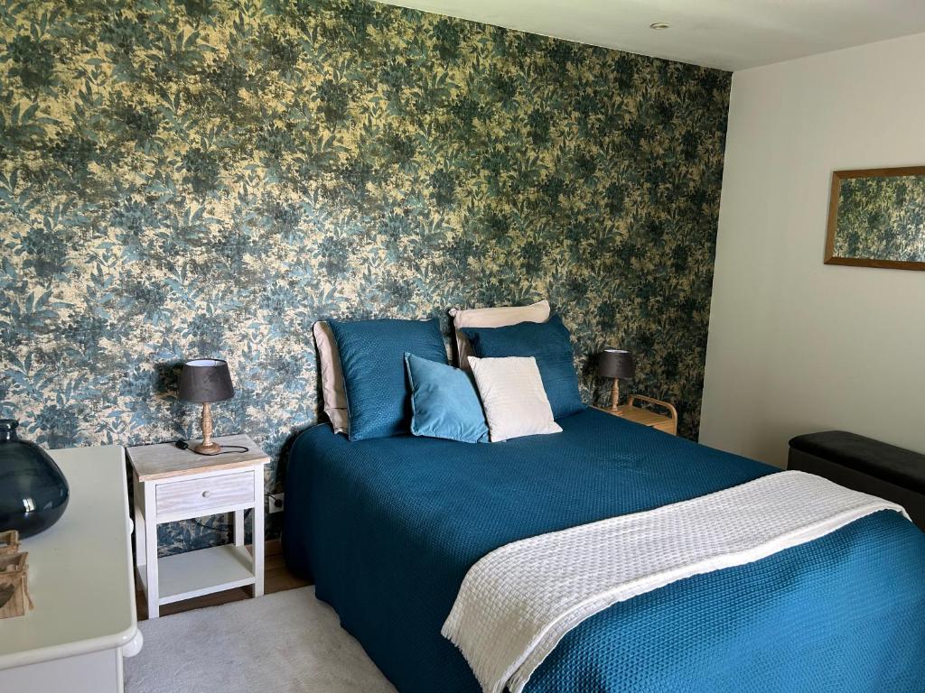 ein Schlafzimmer mit einem blauen Bett mit Blumentapete in der Unterkunft LES GLYCINES in Hières-sur-Amby