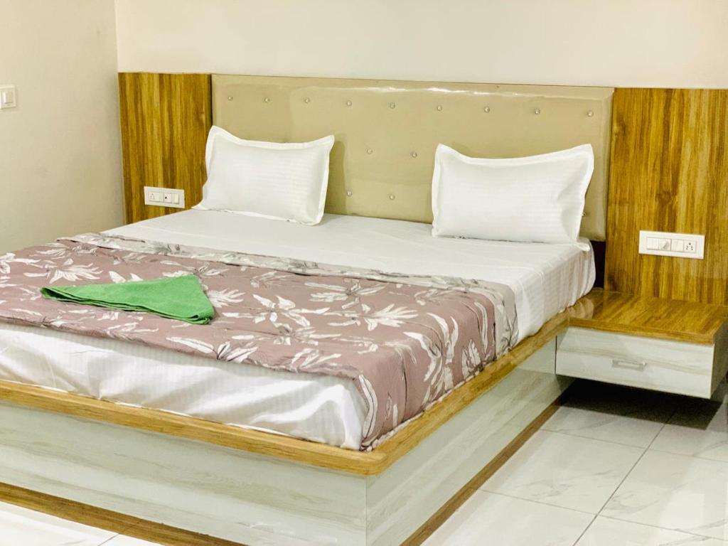 Una cama con dos almohadas y una toalla verde. en THE SILVER TULIP en Ludhiana
