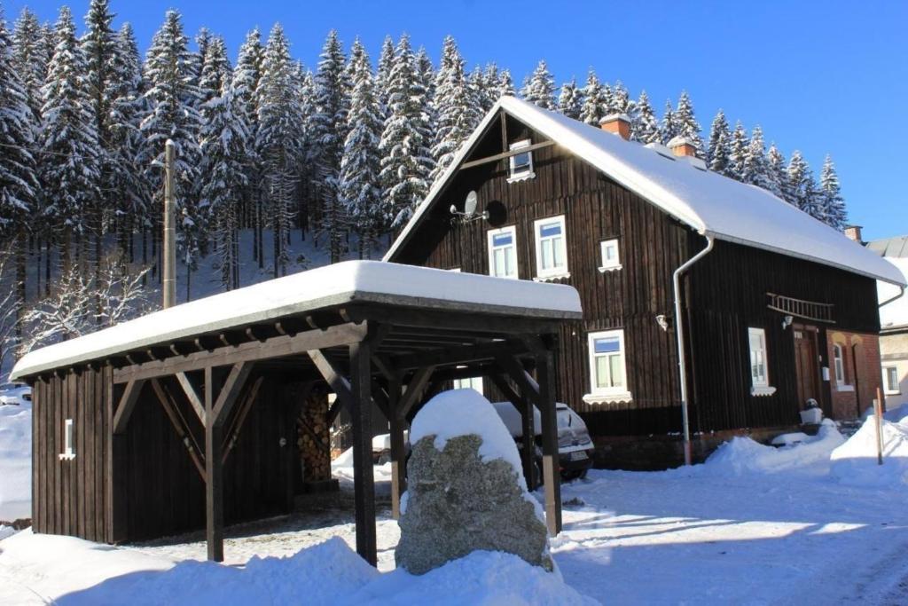 een houten hut met een met sneeuw bedekt dak bij Ferienhaus in Klingenthal mit Terrasse, Grill und Garten in Klingenthal