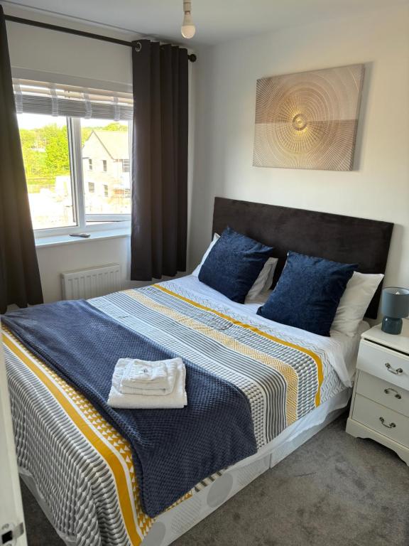 ein Schlafzimmer mit einem Bett mit blauen Kissen und einem Fenster in der Unterkunft Foxglove Close in Middlesbrough