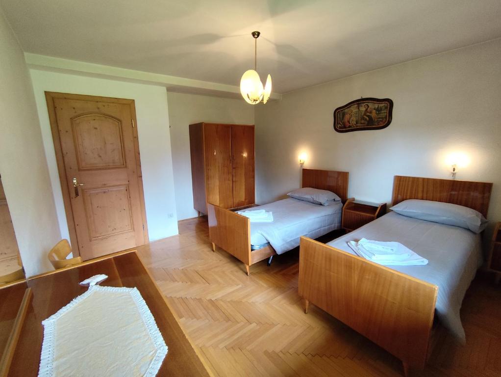 a bedroom with two beds and a table and a door at Panorama mozzafiato in Cortina dʼAmpezzo