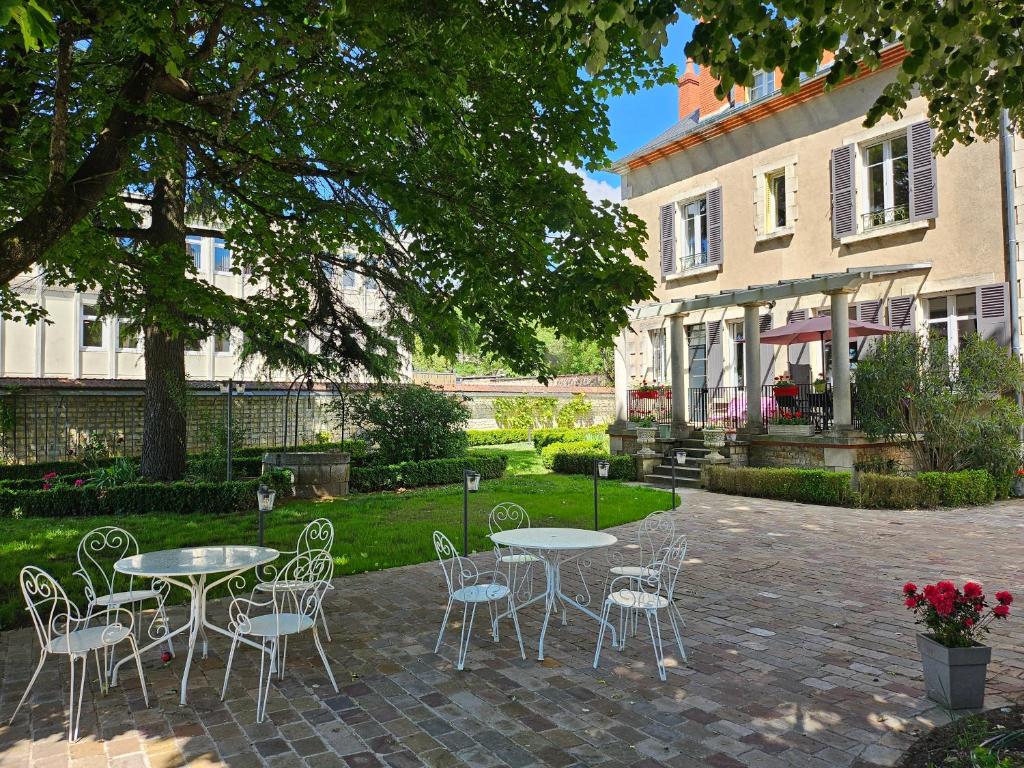 a patio with tables and chairs in front of a house at Chambres d'Hôtes Côté Parc-Côté Jardin avec parking privé gratuit in Nevers