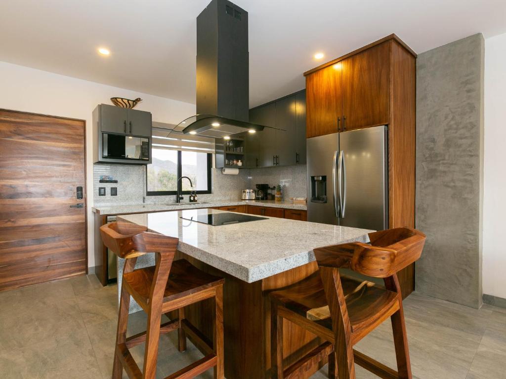 a kitchen with wooden cabinets and a large island with bar stools at Casa Bella Luna in Cabo San Lucas