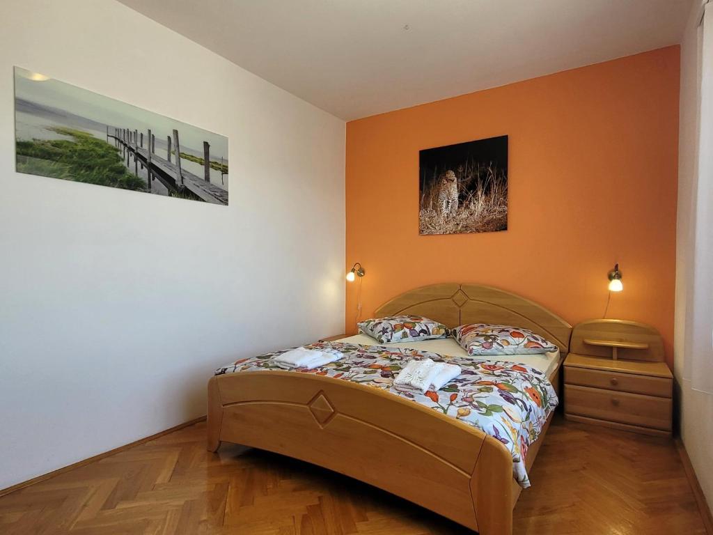 a bedroom with a bed with an orange wall at Apartment Danica in Malinska