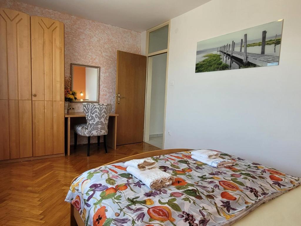 a bedroom with a bed with a flowered bedspread and a desk at Apartment Danica in Malinska