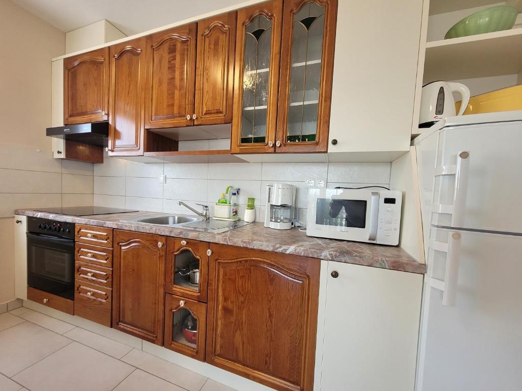 a kitchen with wooden cabinets and a white refrigerator at Apartment Danica in Malinska