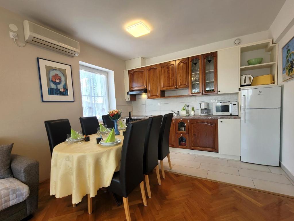 a kitchen with a table with black chairs and a kitchen with a kitchen at Apartment Danica in Malinska