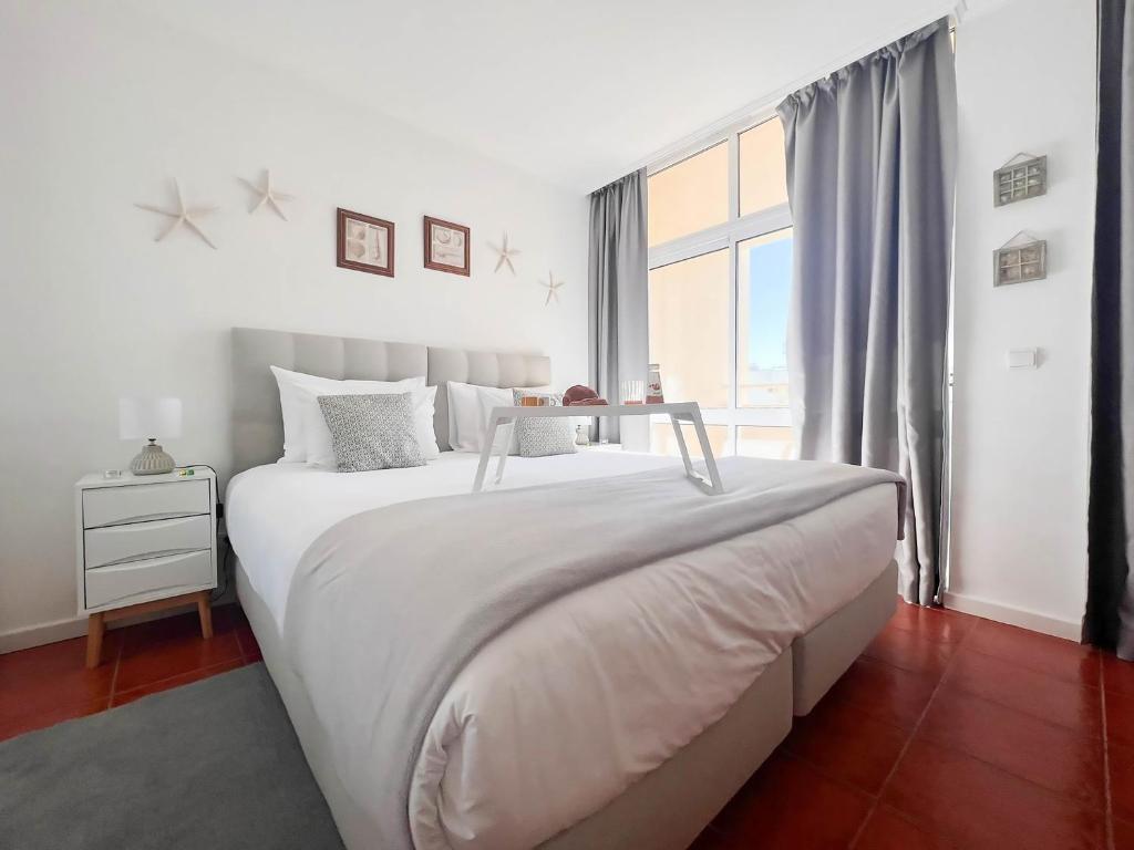 a white bedroom with a large bed and a window at Apartment Rocha Varandas Orquídea in Portimão
