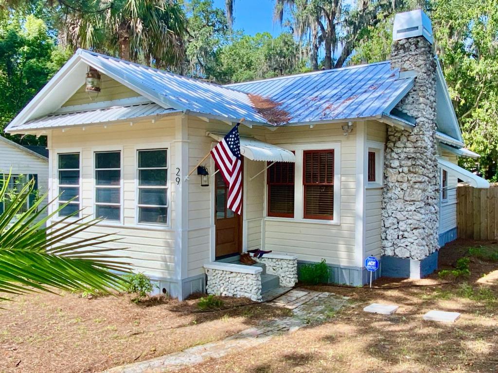uma pequena casa branca com uma bandeira americana em 1940 Cottage on the Nature Coast em Yankeetown