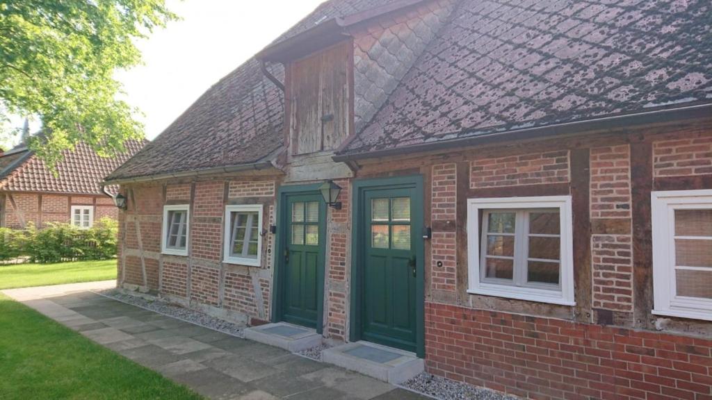 a brick house with green doors and windows at Lüdersburger Strasse 15c in Lüdersburg
