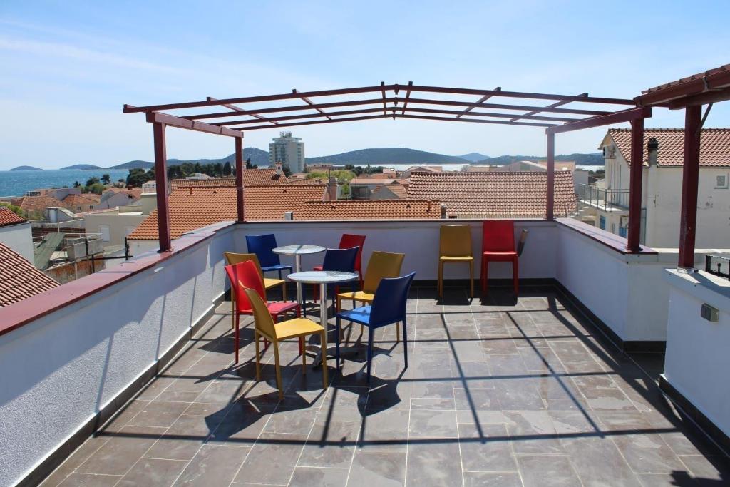 een balkon met kleurrijke stoelen en een tafel op een dak bij Charmante Wohnung in Vodice mit Schöner Terrasse - b61717 in Vodice