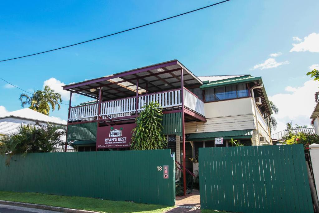 una casa con una valla verde delante de ella en Ryan's Rest Boutique Accommodation, en Cairns