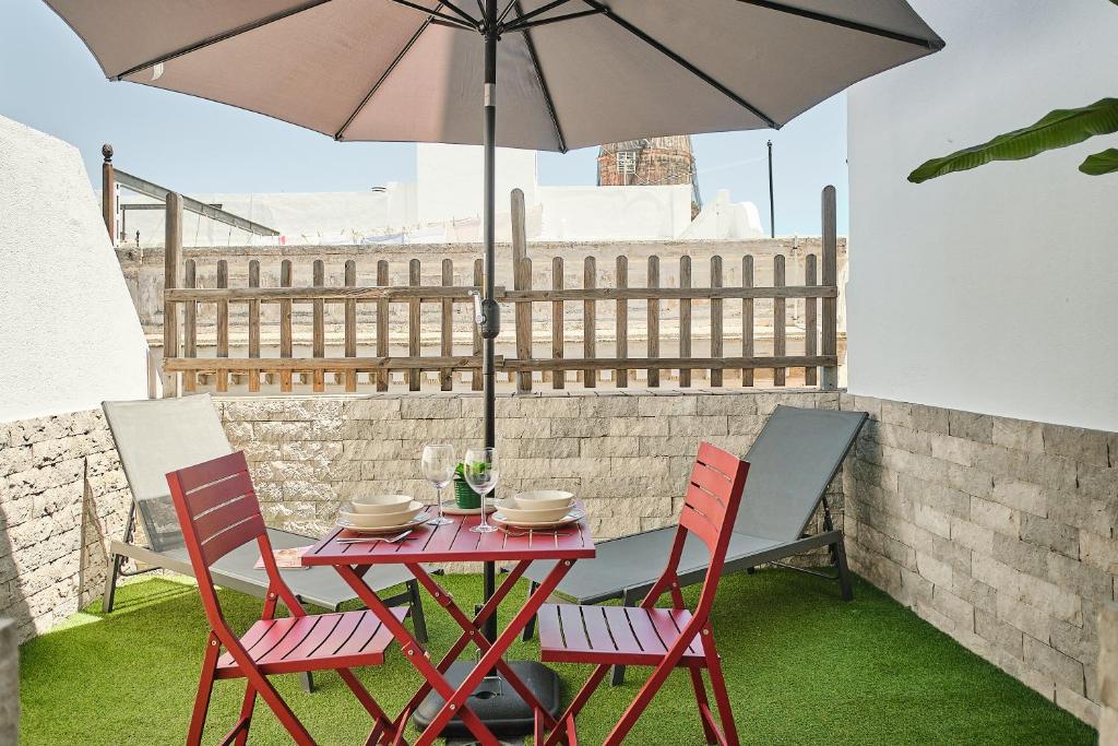 stół i krzesła z parasolem na patio w obiekcie Studio Novena Little Apartments w Kadyksie