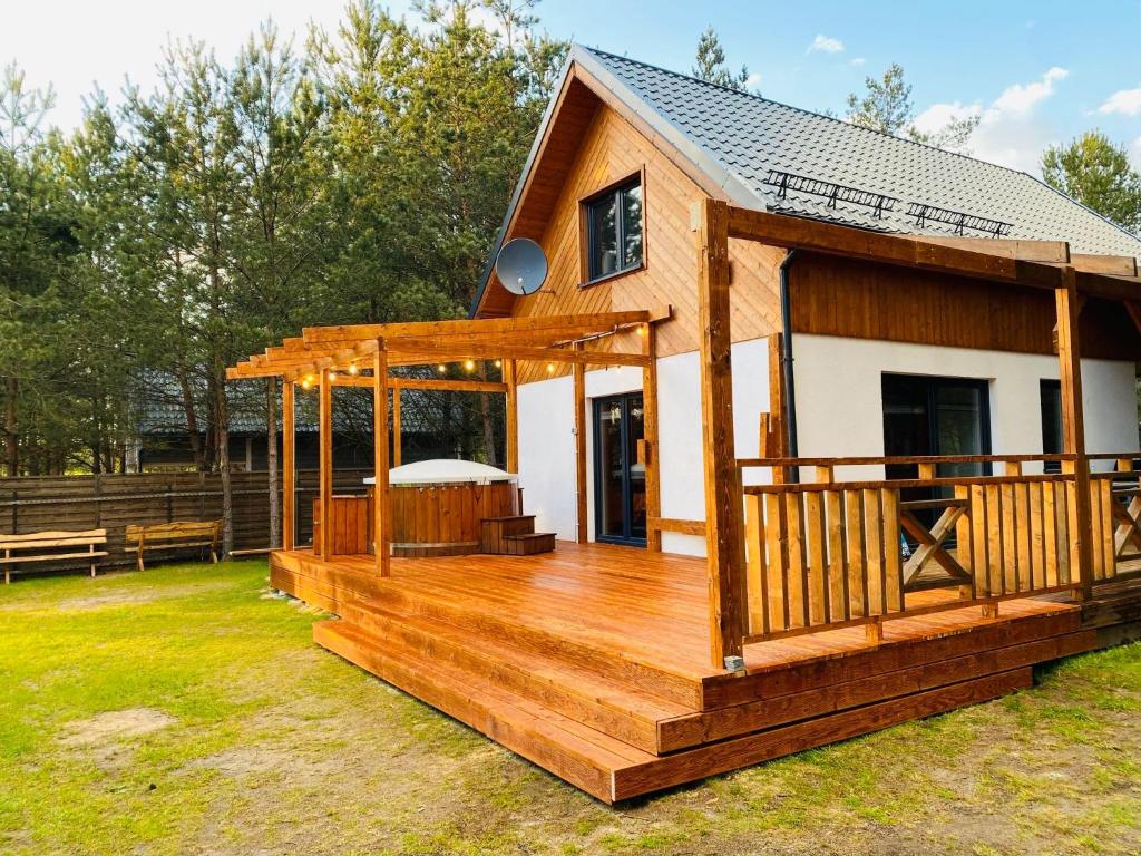 a house with a large wooden deck in a yard at Domek Bartoszylas z sauną i balią in Bartoszylas