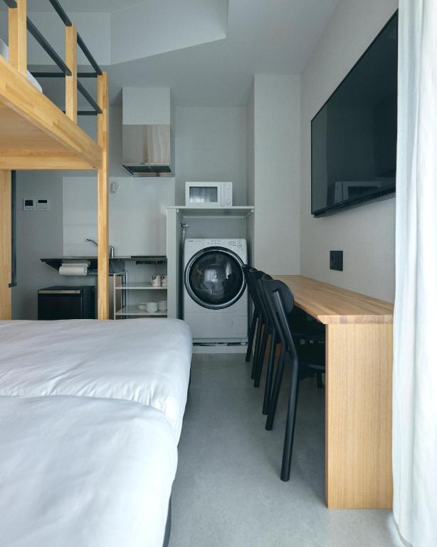 a bedroom with a bed and a desk with a tv at da Haus Shinjuku in Tokyo