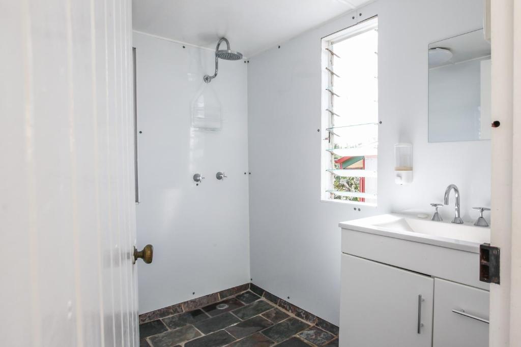 a white bathroom with a shower and a sink at Ryan's Rest Boutique Accommodation in Cairns