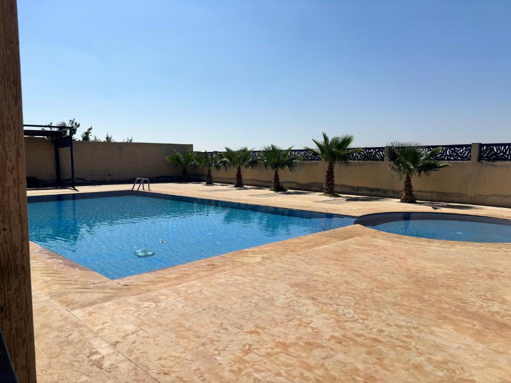 uma piscina com palmeiras ao fundo em Charmante villa avec piscine DAR LUD em Chichaoua