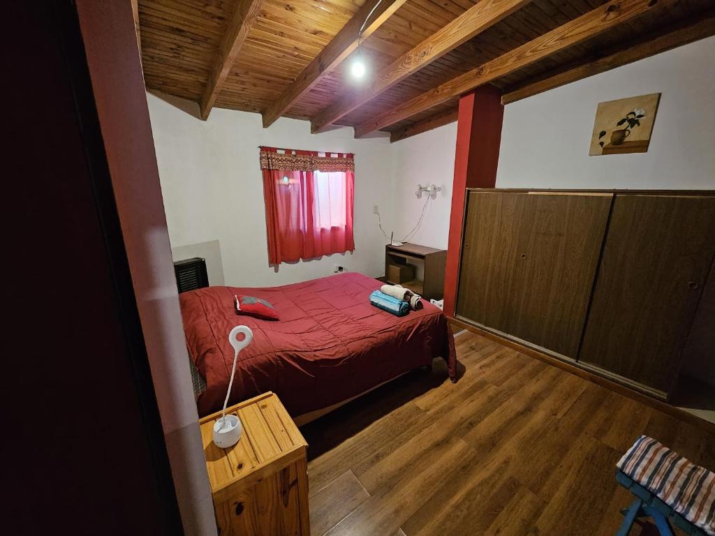 1 dormitorio con cama roja y suelo de madera en Dpto BBB en Zapala