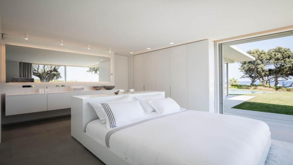 a white bedroom with a large bed and a bathroom at Amamia in Saint-Tropez