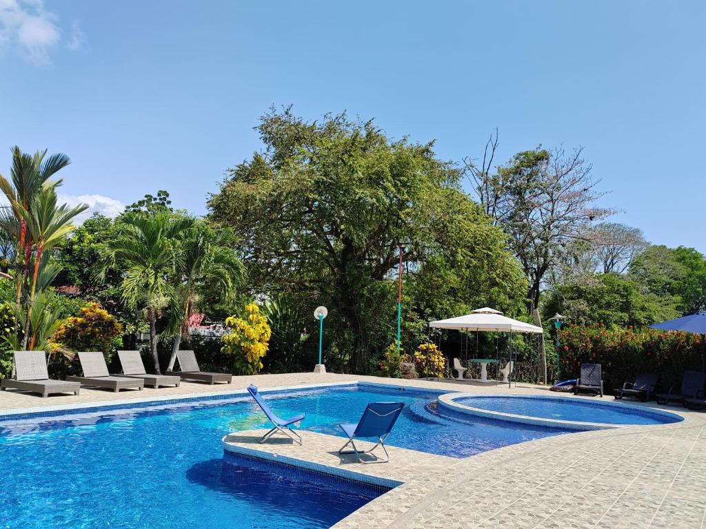 una piscina con 2 sillas y una sombrilla en Hotel Canto de Ballenas, en Uvita