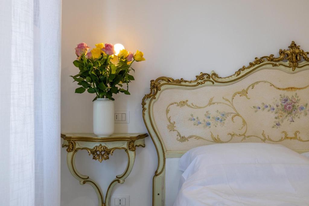 un vaso di fiori su un tavolo accanto a un letto di B&B Oasi a Finale Ligure